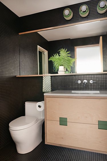 black bathroom with small tiled floor and walls