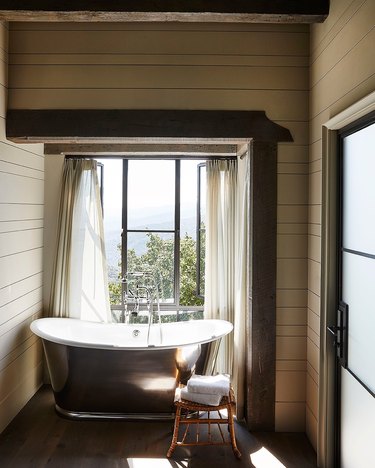 farmhouse bathroom idea with metal freestanding tub and wood beams overhead
