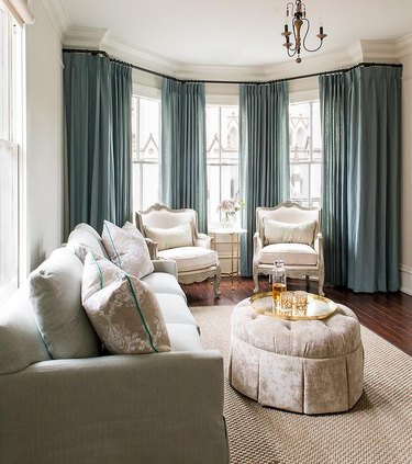 Living room with pewter ottoman and blue curtains.