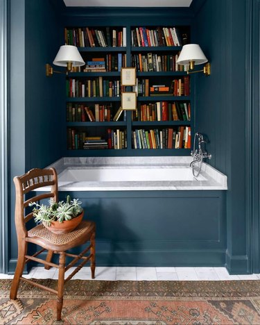 farmhouse bathroom idea with built-in library wall in blue, white marble, and dark wood accents