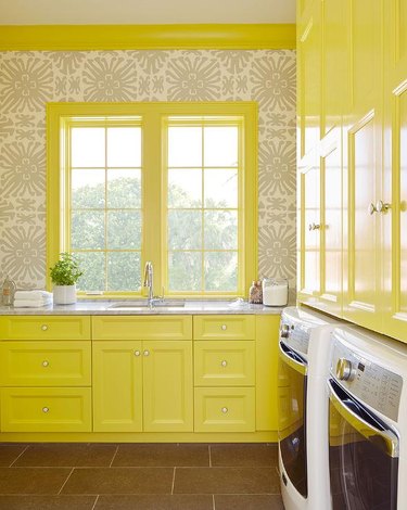 Laundry room with bright yellow cabinets.