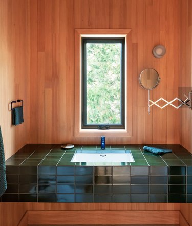 wood paneled bathroom with green tiled counter