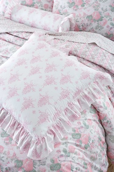 pink toile throw pillow atop a bed with pink rose bedding