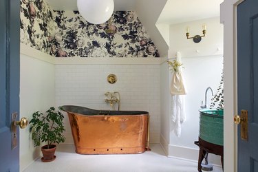 farmhouse bathroom idea with copper soaking tub and white tile and floral wallpapered walls