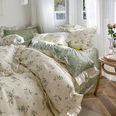messy bed with cream and sage green floral bedding