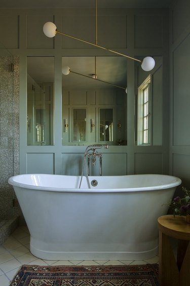 traditional bathroom idea with pedestal tub and modern chandelier