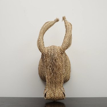 Handwoven sculpture of a donkey made of straw on a white wall