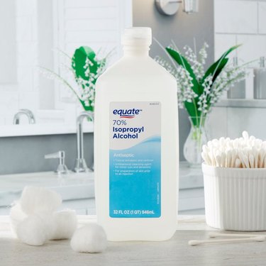 Rubbing alcohol on a bathroom counter with swabs and cotton balls