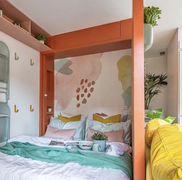 Bedroom with abstract wallpaper and orange framing.