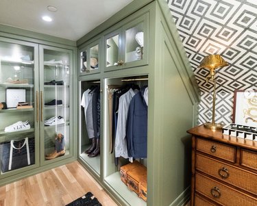 Dressing room with built-in closets, wallpaper, lamp, dresser.