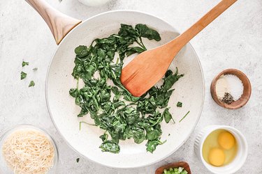 Cooked baby spinach in a white pan