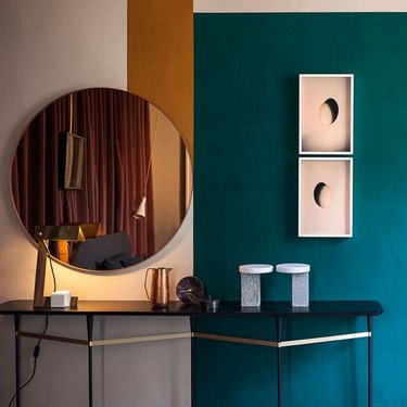 burnt orange and teal color blocked wall with rose gold mirror