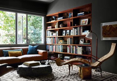 Modern living room with home library, books, chaise lounge, couch, coffee table, rug.