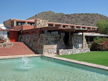 A stone house with a front yard and pool. A mountain range is shown in the background.