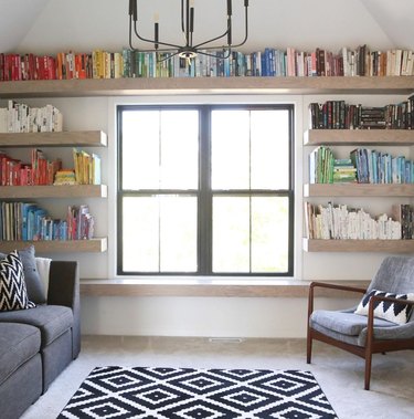 Home library, open shelves, books, couch, chair, rug, chandelier.