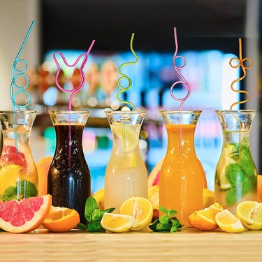 Glasses of different kinds of juice lined up with crazy straws in different colors.