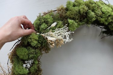 Attaching dried floral bundle to wreath with wire