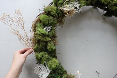 Tucking a long stem of dried baby's breath into wreath