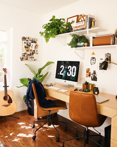 white desert style home office with leather swivel desk chairs and wall--mounted shelving with plants