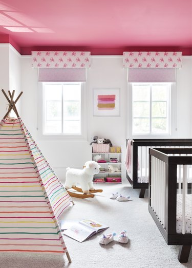 A white painted child's nursery with pink-painted ceiling and accessories