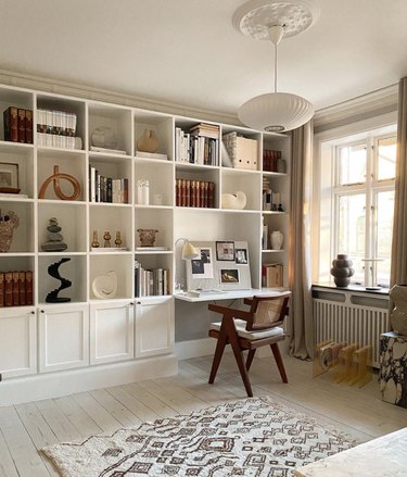 Built in book shelves and desk, pendant light, chairs, art, books, rug.
