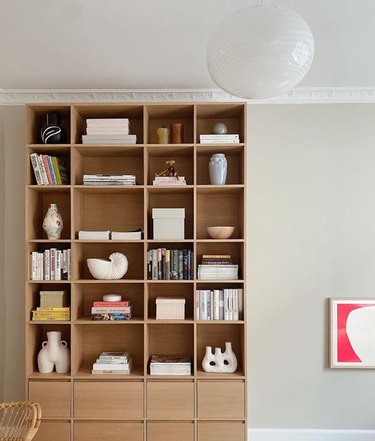 Modern book shelf with drawers, art, books, globe lamp.