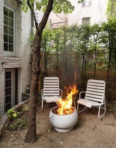 The Novogratz backyard with fire pit and pair of outdoor chairs