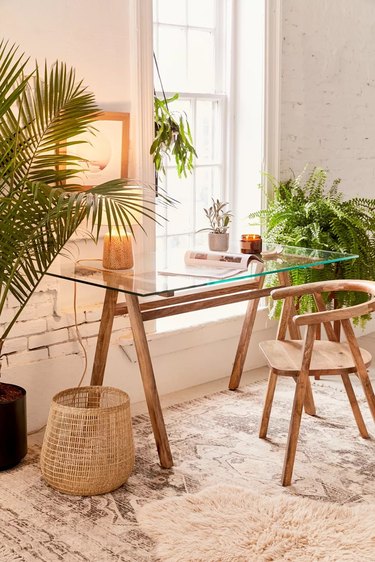 neutral desert style home office with glass desk and lots of plants