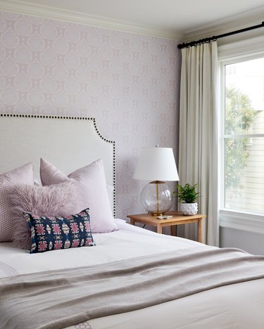 Bedroom with lavender wallpaper and white headboard