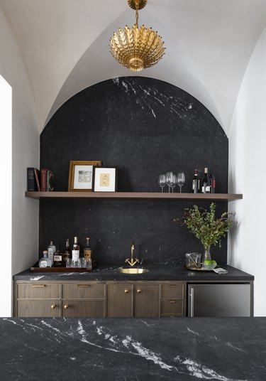 Wet bar with black marble countertop and backsplash