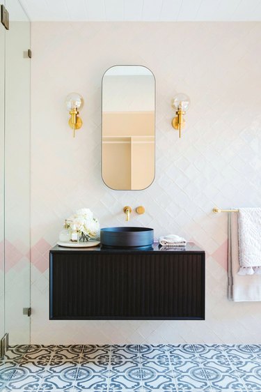 pink bathroom lighting idea with black vanity and glass wall lights