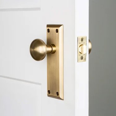 An open white door with a brass doorknob
