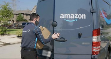 amazon driver holding packages and shutting truck door