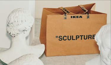 ikea bag with the phrase "sculpture" between two busts