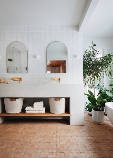 modern organic bathroom with unglazed natural terracotta zellige tiled floor and contemporary freestanding bathtub