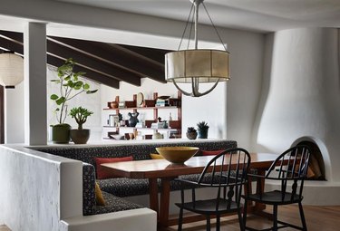 Banquette seating with rectangle table, black farmhouse dining chairs, pendant light, fireplace,