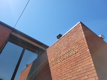 Exterior of brick building with glass windows beneath a clear blue sky.