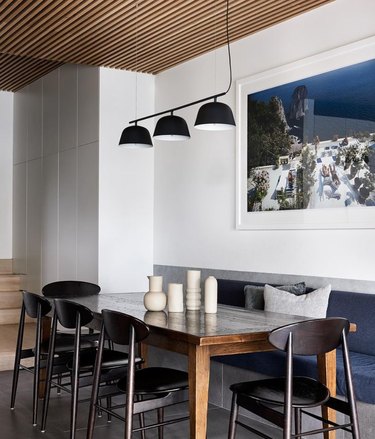 Modern kitchen with banquette seating, modern triple pendant light, artwork.