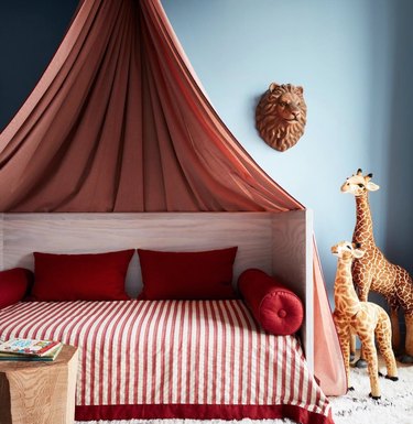 Kids canopy bed, stuffed animals, pillows, striped quilt.