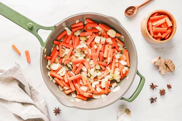 Carrot, onions, and garlic in a green skillet