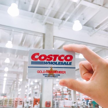 Hand holding up a Costco membership card in the store