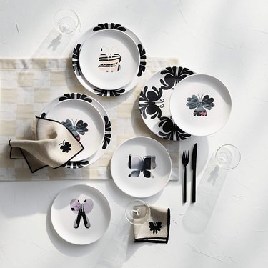 Several plates featuring butterflies on a white surface with butterfly napkins and a beige checkerboard placemat.
