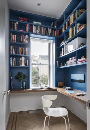 small blue home office nook with blue built-in shelving, white office chair