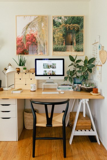 boho home office with two large photograph prints hanging above the desk, plants