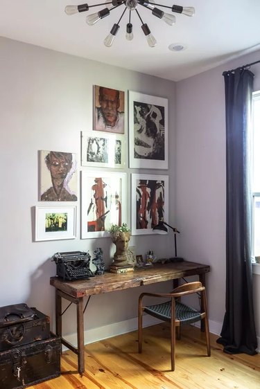 eclectic home office with gallery wall hanging above the vintage wooden desk 