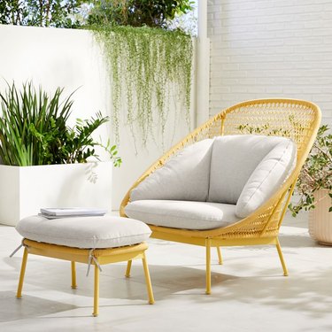 A light brown rattan lounge chair and ottoman with a light gray cushion.