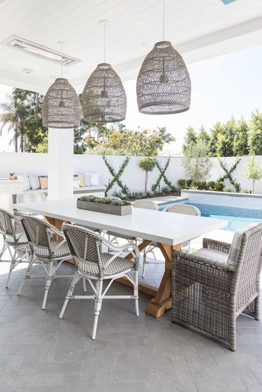 coastal grandmother decor idea for patio with dining table and rattan chairs and pendant lighting