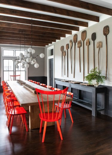 Dining room with dark wood floors, gray walls, red dining chairs, globe chandelier.