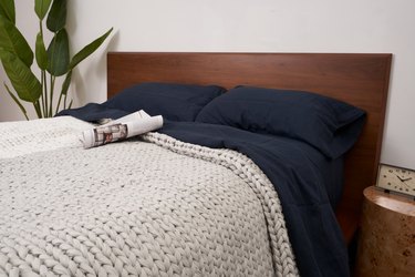 bearaby the hugger blanket on bed with navy bedding