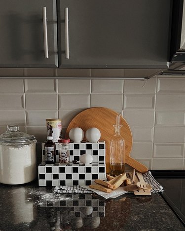 Black and white checkered tiled display stand by SOL STUDIO on a kitchen countertop
